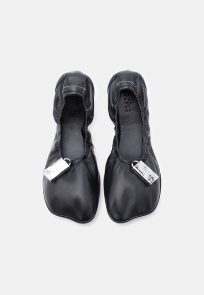 Μαύρα μπαλαρίνες από δέρμα με ελαστικές άκρες, στρογγυλή μύτη, λεία υφή και μεταλλική ταυτότητα. Η σόλα είναι ευέλικτη και επίπεδη.