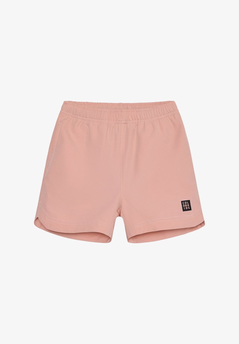 Shorts rose clair en tissu doux avec une ceinture élastique, deux poches latérales, et une étiquette logo noire en bas à gauche.