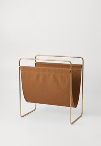 Metalni držač za časopise s zlatnim okvirom i smešnim platnenim džepom. Glatka površina, minimalistički dizajn i otvorena struktura za jednostavan pristup.