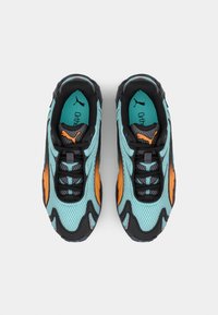 Tyrkysové síťované tenisky s černými a oranžovými akcenty. Mají texturované panely, polstrovaný límec a gumovou podrážku. Viditelné šňůrky a loga.