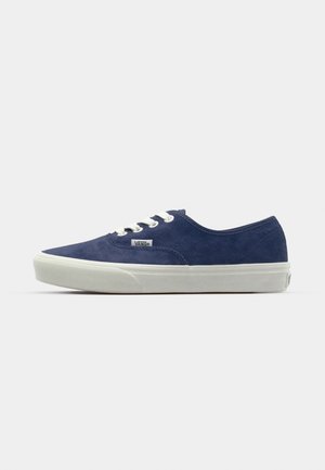 Zapatillas de ante azul marino con punta redondeada, suela de goma blanca y ojales a juego. Cuenta con un pequeño logo de Vans en el costado.