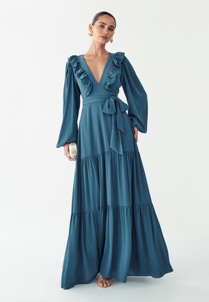 Morsko zelena dolga obleka z nabrano izrezom in dolgimi rokavi, z zavezovanjem v pasu in večstopenjskim robom. Gladek material s tekočo silhueto.