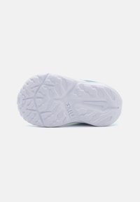 Hvitt sportsko såle med teksturert gummioverflate, med bølgemønstre og tydelige forankringsplugger for grep. Nike-logo preget.