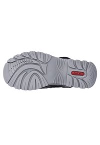 Svart sportskosula med en grå gummibotten, utrustad med ett mönster för grepp och en röd logotypdetalj.