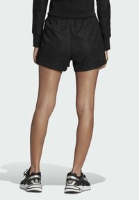 Svarta sportshorts av texturerat material med elastisk midja. I kombination med svarta och vita sportskor.