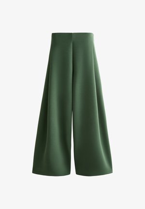 Magasderekú, széles szárú nadrág egyszínű sötétzöld anyagból, sima textúrával és középen végigfutó varrással minden lábszáron.