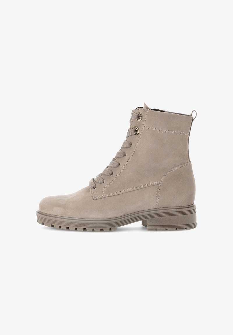 Bottines en suède beige avec un bout rond, un laçage à l'avant et une semelle en caoutchouc texturée. Comprend des coutures décoratives et une languette à l'arrière.