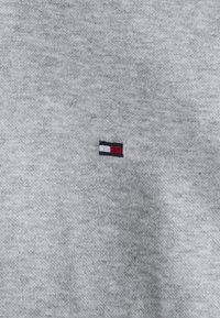 Grå bomulds sweatshirt med et lille broderet logo med et rektangel i rød, hvid og blå på venstre brystområde.