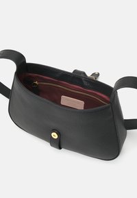 Musta nahkainen laukku, jossa on teksturoitu pinta, kultaiset metalliosat, sisäinen vetoketjutasku ja burgundinpunainen vuori. Laukussa on napinapitukiinnitys ja olkahihna.