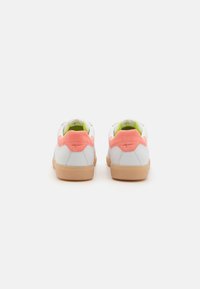 Sneakers bianchi in pelle con dettagli in camoscio rosa sul tallone, fodera verde e suola in gomma beige. Presentano una texture liscia e un design minimale.