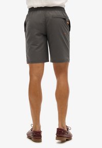 Grijze shorts met een elastische tailleband, zijzakken en een met rits sluitende achterzak, met oranje accenten en een gladde textuur.