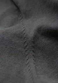 Tessuto di maglia nera con una finissima trama, caratterizzato da cuciture visibili che creano un motivo sottile lungo la cucitura.