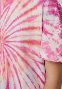 Koszulka z krótkim rękawem w tie-dye z spiralnym wzorem w odcieniach różu, pomarańczy i bieli; wykonana z miękkiej bawełny w luźnym kroju.