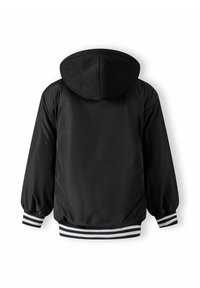 Veste noire avec capuche, fabriquée en matière lisse. Présente une ribambelle noir et blanc aux poignets et à la taille.