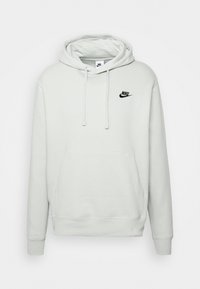 Vaaleanharmaa Nike-huppari, jossa on kengurupussi, säädettävä nauhakuusi ja pieni musta logo rinnassa. Pehmeää puuvillamateriaalia.