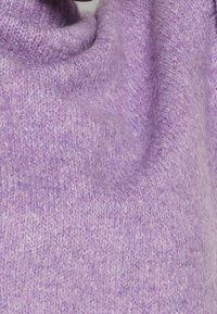 Tissu en tricot doux et pelucheux de couleur violet clair, montrant la texture et les plis tombants.