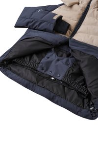 Padded jacket w kolorze beżowym i granatowym. Posiada zamek błyskawiczny, elastyczne mankiety oraz napy. Podszewka wewnętrzna o gładkiej fakturze.