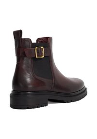 Burgundy leather ankle boot with black elastic side panels, a gold buckle accent, and a chunky black rubber sole. Smooth texture.