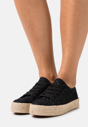 Black lace-up shoes with a textured black fabric upper and woven jute-style platform sole. Low-cut design with round toe and flat laces.