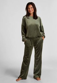 Fluwelen loungewear set in olijfgroen, met een loszittende top met lange mouwen en broek met brede pijpen en elastische tailleband.