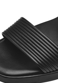Schwarze Rutschsandale mit einem breiten Riemen und vertikaler Rippung, aus strukturiertem synthetischem Material gefertigt und mit einer sanft geschwungenen Fußbett.