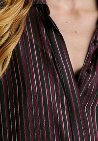 Gestreept shirt in zwart met bordeauxrood en zilveren strepen, voorzien van een kraag en knoopdetails. Gladde textuur met een subtiele glans.