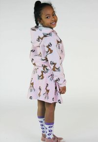 Sudadera rosa con estampado de renos y falda a juego, con cintura elástica. Tejido texturizado, complementado con calcetas estampadas y zapatos rosas.