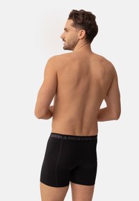 Boxer da uomo neri con una fascia elastica grigia su cui sono stampate le parole "DANISH" e "ENDURANISH". Tessuto morbido e elastico, vestibilità aderente.