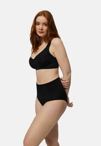 Conjunto de lencería negra que incluye un sujetador acolchado con tirantes anchos y bragas de talle alto. La tela parece suave con branding minimalista.