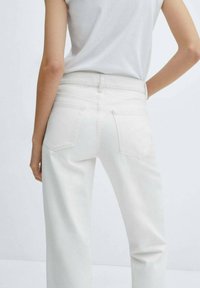 Vaqueros blancos de mezclilla con diseño de pierna recta, que cuentan con bolsillos traseros y una textura suave. La cintura es ajustada y lisa.