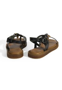 Schwarze Ledersandalen mit verstellbaren Knöchelriemen, braunen gepolsterten Sohlen und dekorativen Perlen auf der Oberseite. Flaches, offenes Design für die Zehen.