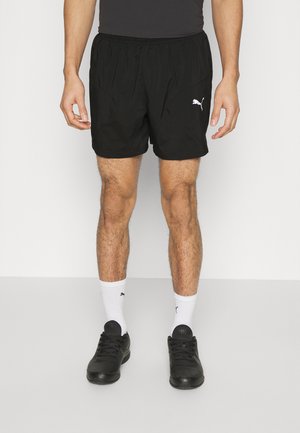 Pantalones cortos deportivos negros hechos de tela ligera, con una cinturilla elástica, bolsillos laterales y un pequeño logotipo blanco en el dobladillo izquierdo.