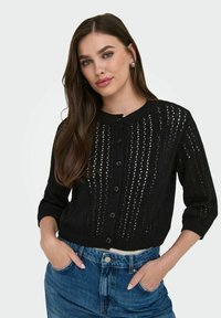 Crna pletena cardigan jakna s dizajnom na gumbi, rukavima do tri četvrtine i detaljima otvorenog uzorka.