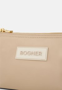 Pochette in nylon beige con zip dorata. Presenta un'etichetta cremosa testurizzata con la scritta "BOGNER" in rilievo. Superficie liscia con cuciture a contrasto.