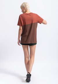 Korte mouwen t-shirt met een kleurblokontwerp in rood en bruin. Gemaakt van katoen, met een ronde halslijn en een ontspannen pasvorm.