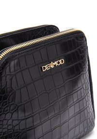 Sac en simili cuir noir avec un motif crocodile, doté d'une fermeture éclair dorée et du nom de marque "DERİMOD" embossé sur le devant.