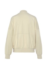 Hellbeige Sweatshirt mit hohem Kragen, überschnittenen Schultern und elastischem Bund. Glatte Textur, leicht lockere Passform und minimales Design.
