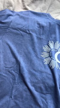 Dunkelblaue Baumwoll-T-Shirts mit kurzen Ärmeln, mit einem weißen Sonnen- und Mondgrafikdesign. Weicher Stoff mit leichten Falten.