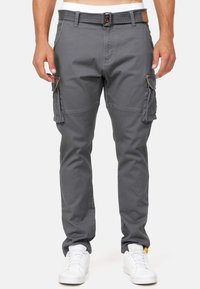 Pantaloni cargo grigi con tasche laterali, fronte piatto, passanti per cintura e un accento in pelle sulla vita posteriore. Il tessuto sembra resistente e liscio.