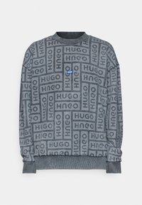 Sudadera gris con un patrón repetido de la palabra "HUGO" en diferentes tonos. Cuello y puños acanalados, textura de tela suave.