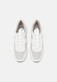 Des baskets blanches avec une tige en textile gris doux, des lacets blancs, de subtils accents beiges et une semelle en caoutchouc lisse.