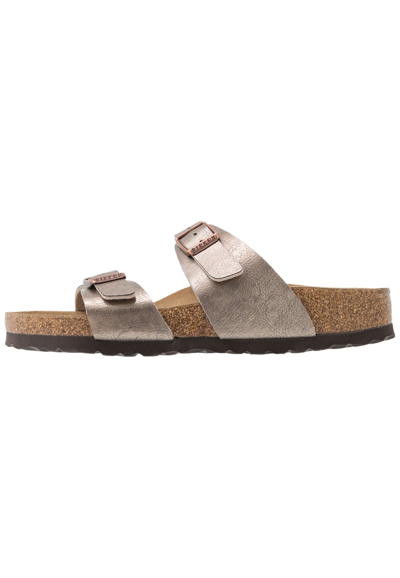 Metallisch silberne Sandalen mit zwei verstellbaren Riemen, einem Korkfußbett und einer schwarzen Gummisohle mit einem strukturierten Profil.