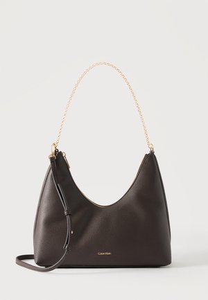 Sac à épaule en cuir brun foncé avec poignée chaîne dorée, longue bandoulière réglable et logo Calvin Klein à l'avant.