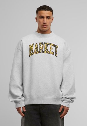 Grå hettegenser med rund hals og oversized passform. "MARKET" i kamuflasjemønster over brystet. Ribbestrikkede mansjetter og nederkant.