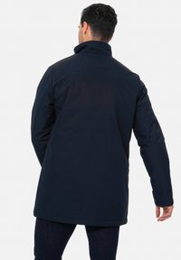 Cappotto isolante blu navy con colletto alto e maniche lunghe, caratterizzato da una texture liscia e un taglio dritto con un retro leggermente allungato.