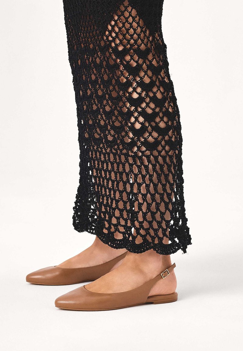 Brązowe skórzane baleriny z paskiem z tyłu i szpiczastym noskiem; czarna sukienka z fakturą szydełkową, posiadająca falowany brzeg i otwarty wzór splotu.