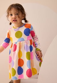 Robe à manches longues avec de grosses pois colorés. Fabriquée en tissu côtelé, elle présente un col rond et un ourlet festonné.