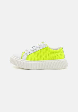 Baskets en mesh jaune fluo avec semelle et bout en caoutchouc blanc. Présentent des lacets ronds et une surface texturée pour la ventilation.