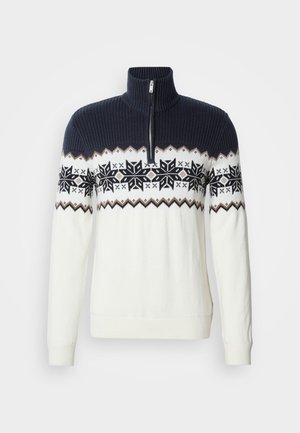Maglione lavorato a maglia con collo con cerniera, parte superiore blu scuro e corpo bianco con un motivo decorativo di fiocchi di neve neri e accenti geometrici.