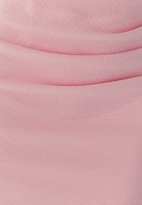 Svetlo roza tkanina z nežnim teksturiranim vzorcem, ki prikazuje valovite črte in ima mehak, gladek zaključek. Idealna za oblazinjenje ali mehke pohištvene dodatke.